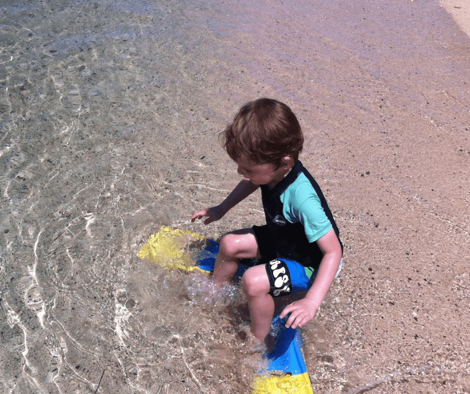 Lukas sitting on the waters edge of his flippers on