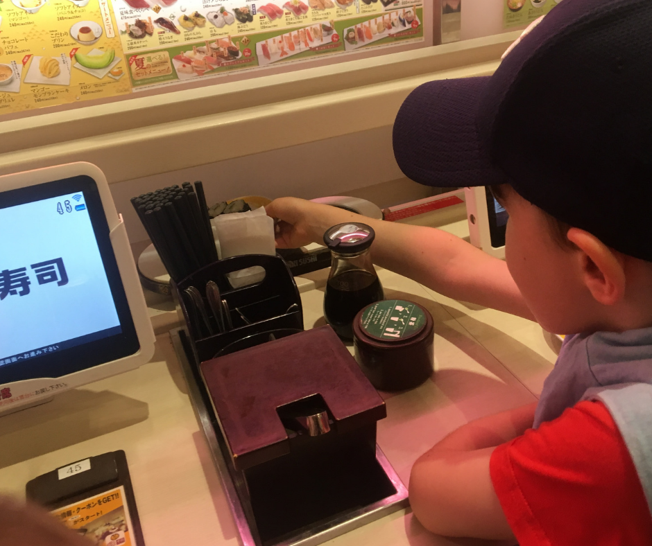 Lukas collecting his order from the sushi train