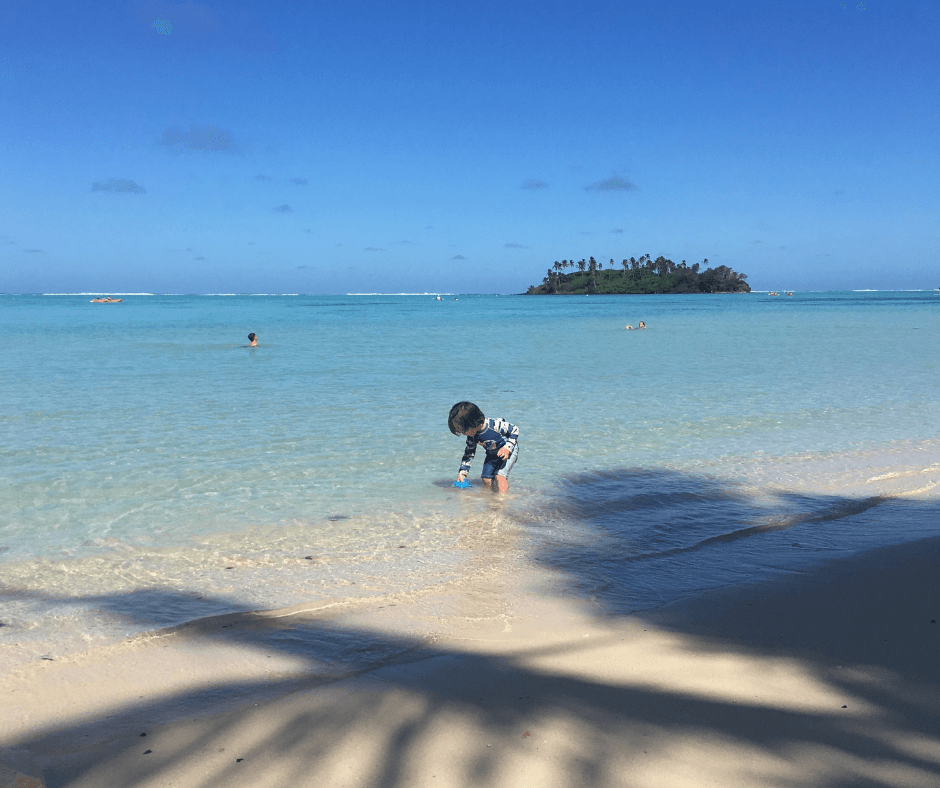 Sawyer with his feet in the water, looking for rocks