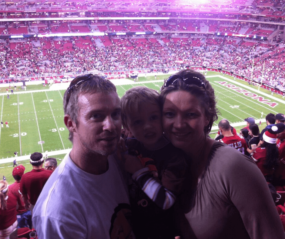 family posing for a photo with the pitch in the back drop