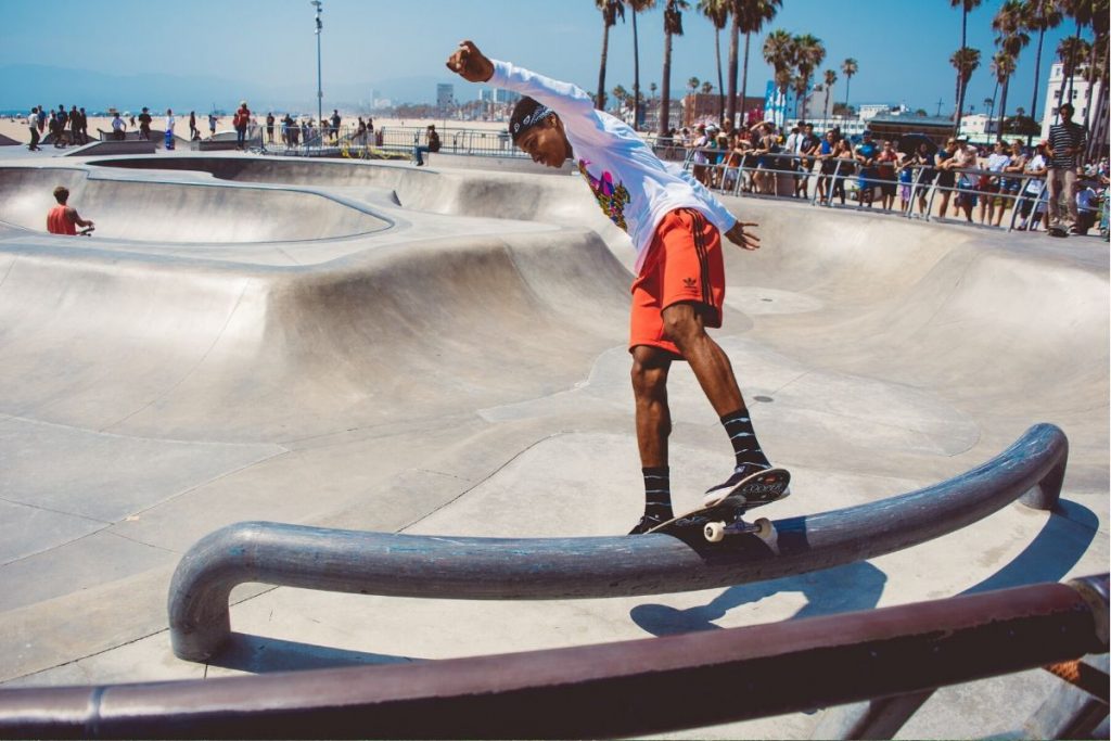 Talented skateboarder riding a rail in the bowl with a crowd looking on