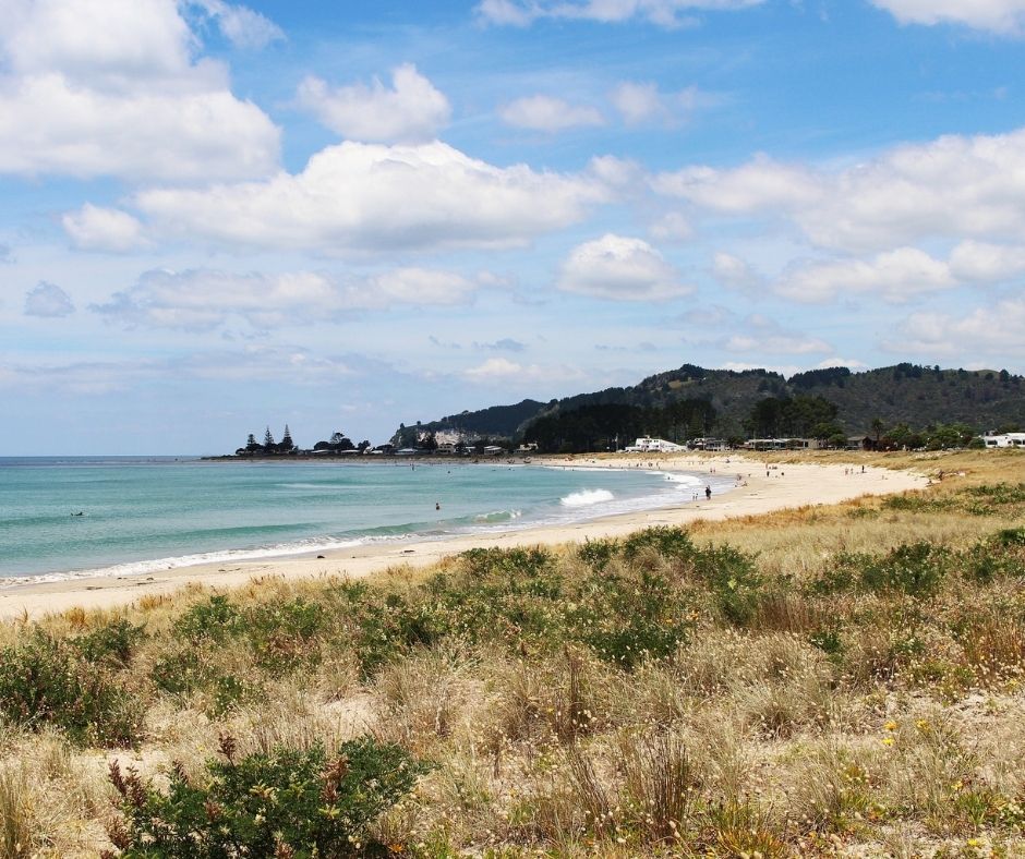 Whangamata coastline, long stretch of beach with waves rolling in