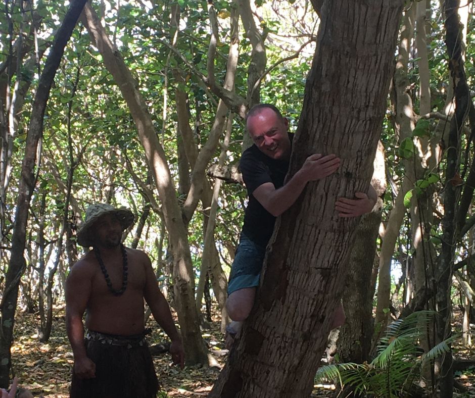 Matt climbing a coconut tree, not getting far as the guide looks on