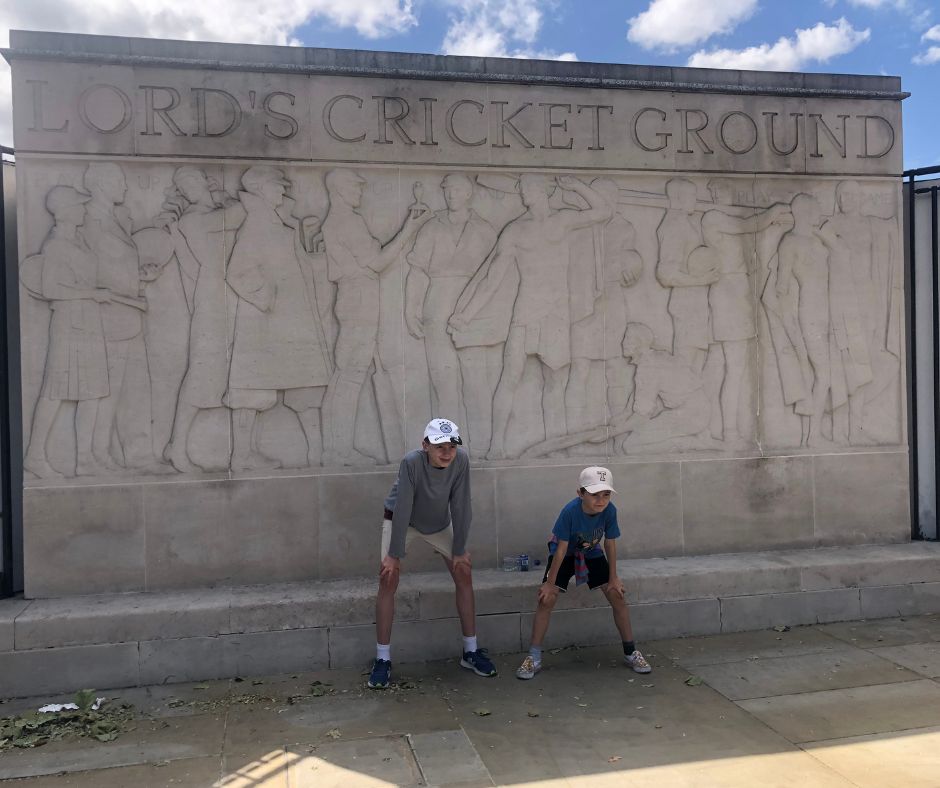 Boys posing outside Lords next to the famous concrete wall sign