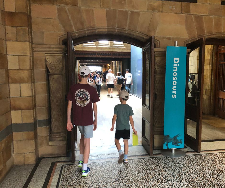 Both boys walking through the Dinosaur entry