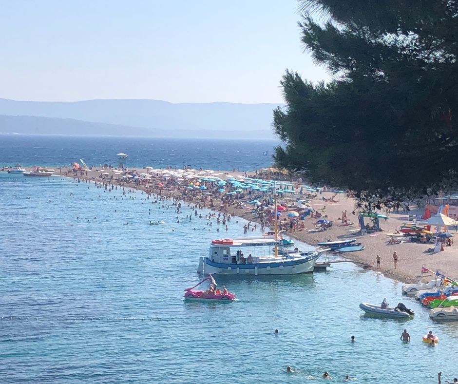 Arriving at Zlatni Rat beach, looking down the peninsula at the people and shore line umbrellas