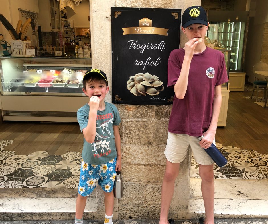 The boys biing into a rafioli treat outside the shop