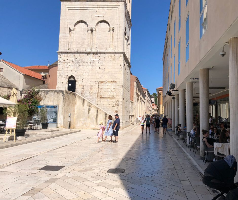 Looking down a paved street lined with cafes and old buildings