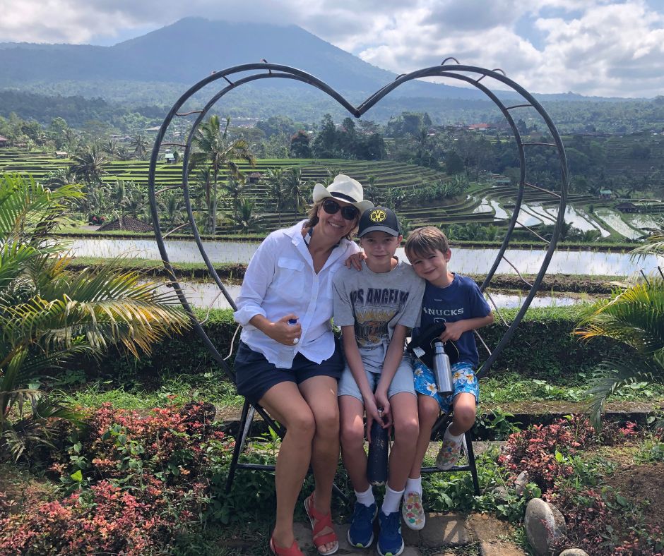 Connie and the boys sitting in a heart shaped seat with Jatiluwih Rice Terraces in the background