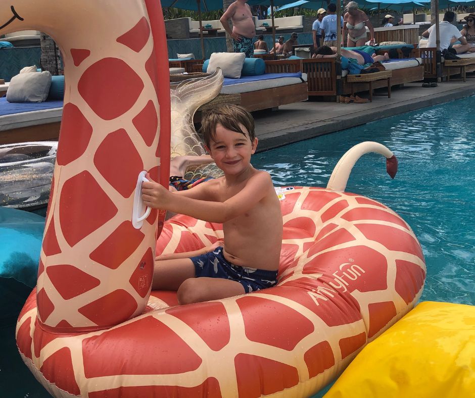 Sawyer chilling on the inflatable giraffe and the pool