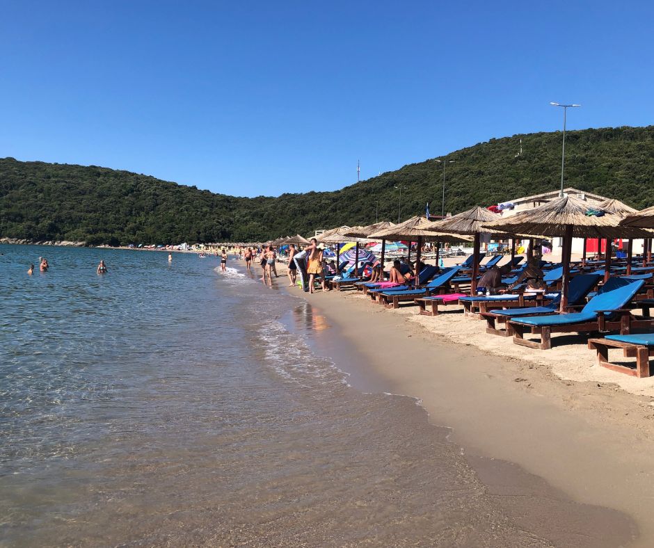 Jaz Beach shoreline with sunloungers, and people swimming and relaxing