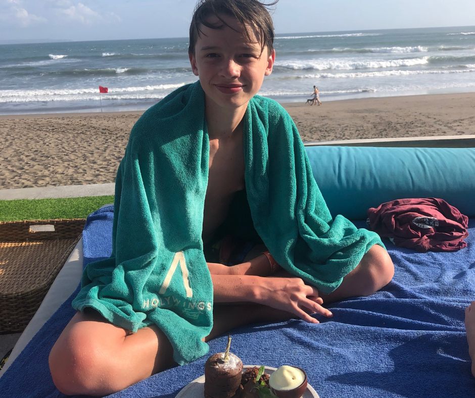Lukas sitting on the day bed with a birthday cake treat from the Atlas Beach Club