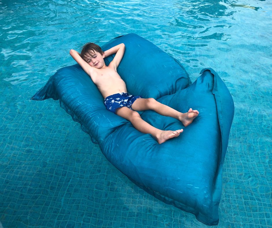 Sawyer relaxing in the pool on an inflatable pillow. Atlas Beach Club with kids is a dream