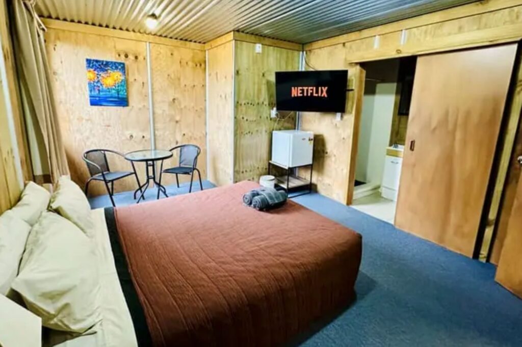The Crossing Lodge accommodation bedroom, with bed, TV, and bathroom